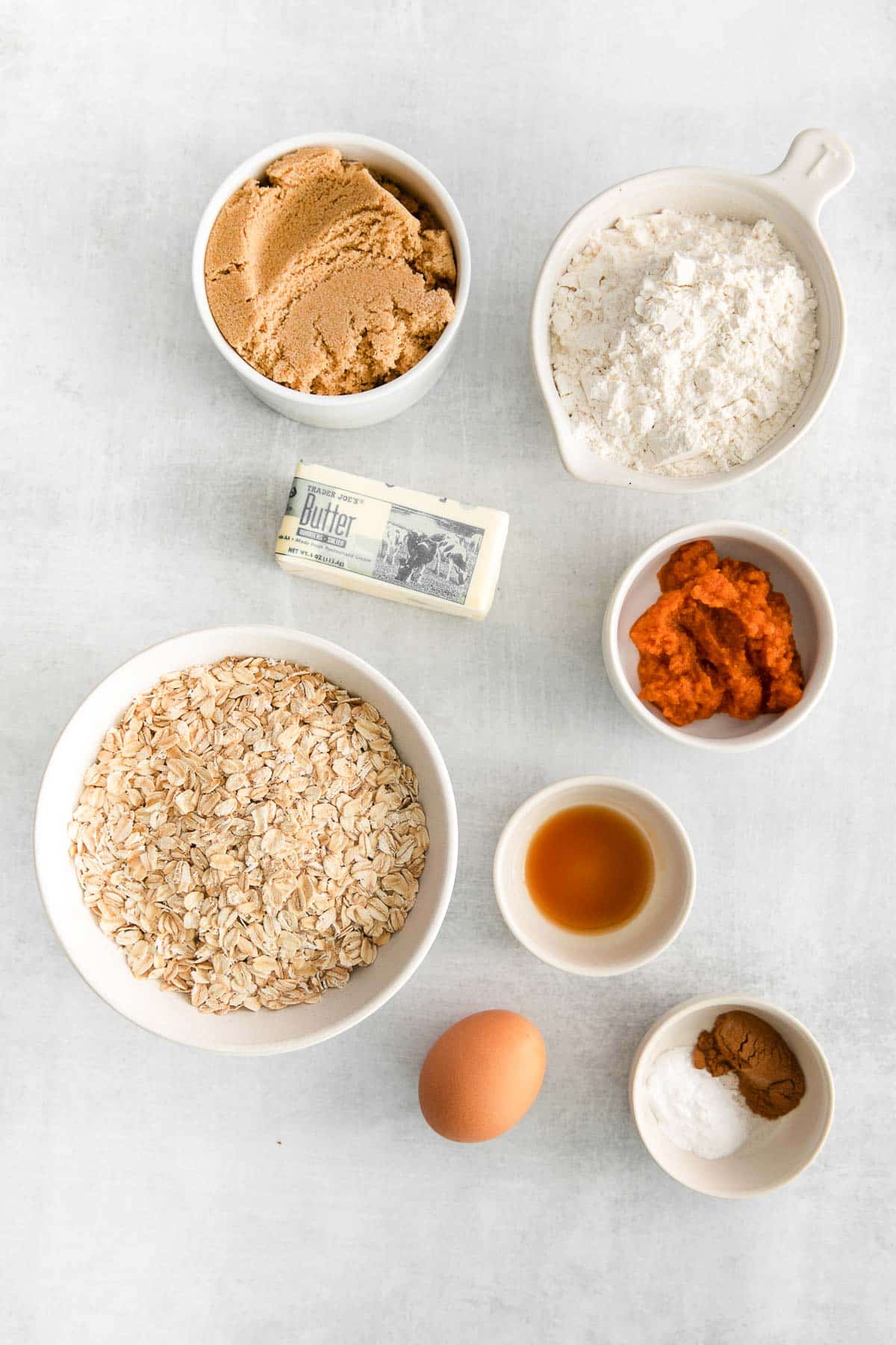 several white bowls with ingredients for apple butter - oatmeal, flour, pumpkin puree, brown sugar, pumpkin pie spice, one egg, butter, and vanilla extract.
