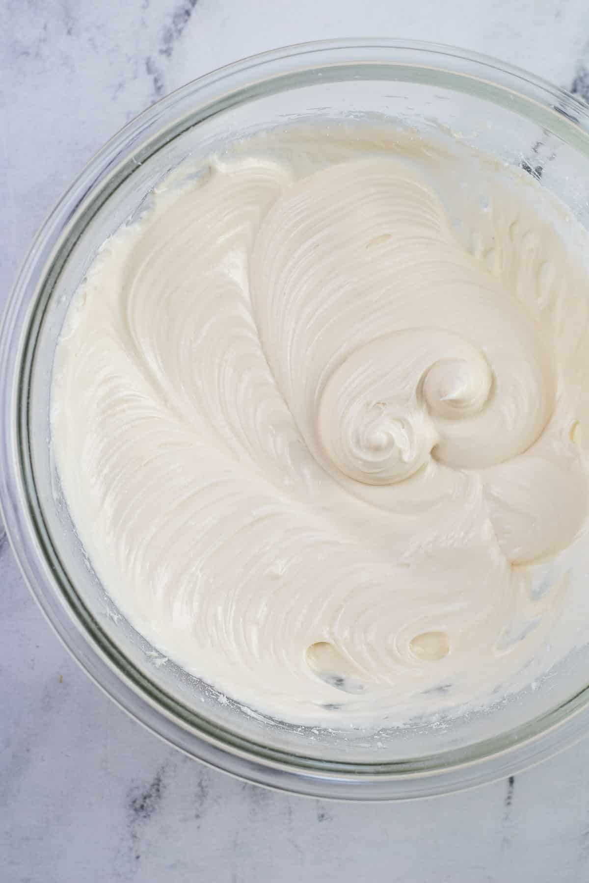 fluffy cream cheese frosting blended in a big glass mixing bowl.