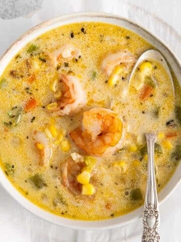closeup of shrimp corn chowder in a white bowl with spoon in it.