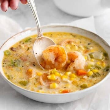 spoon dipping into shrimp corn chowder in a white bowl