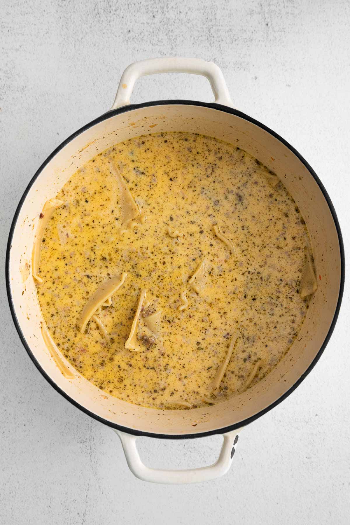 creamy soup with lasagna noodles in a white soup pot.
