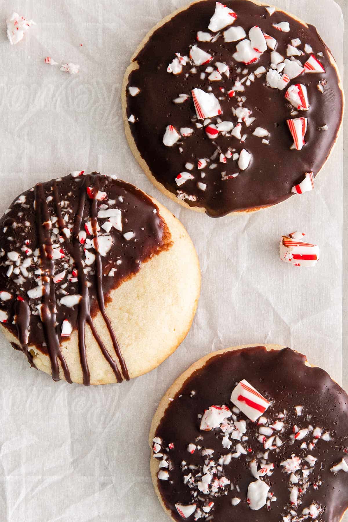 closeup of three chocolate covered cookies with crushed candy canes on top.