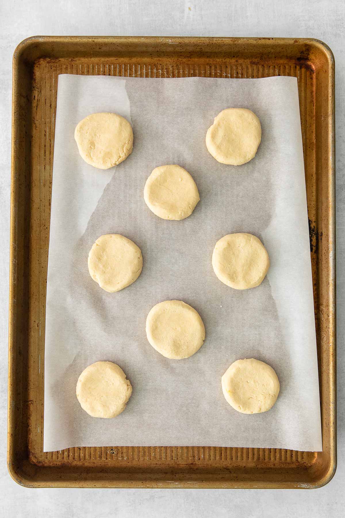 eight uncooked shortbread cookies on a parchment lined baking sheet.