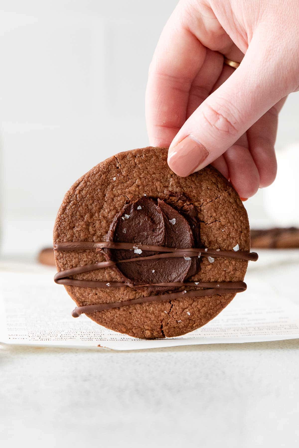 woman's hand holding a chocolate cookie with chocolate genache center.