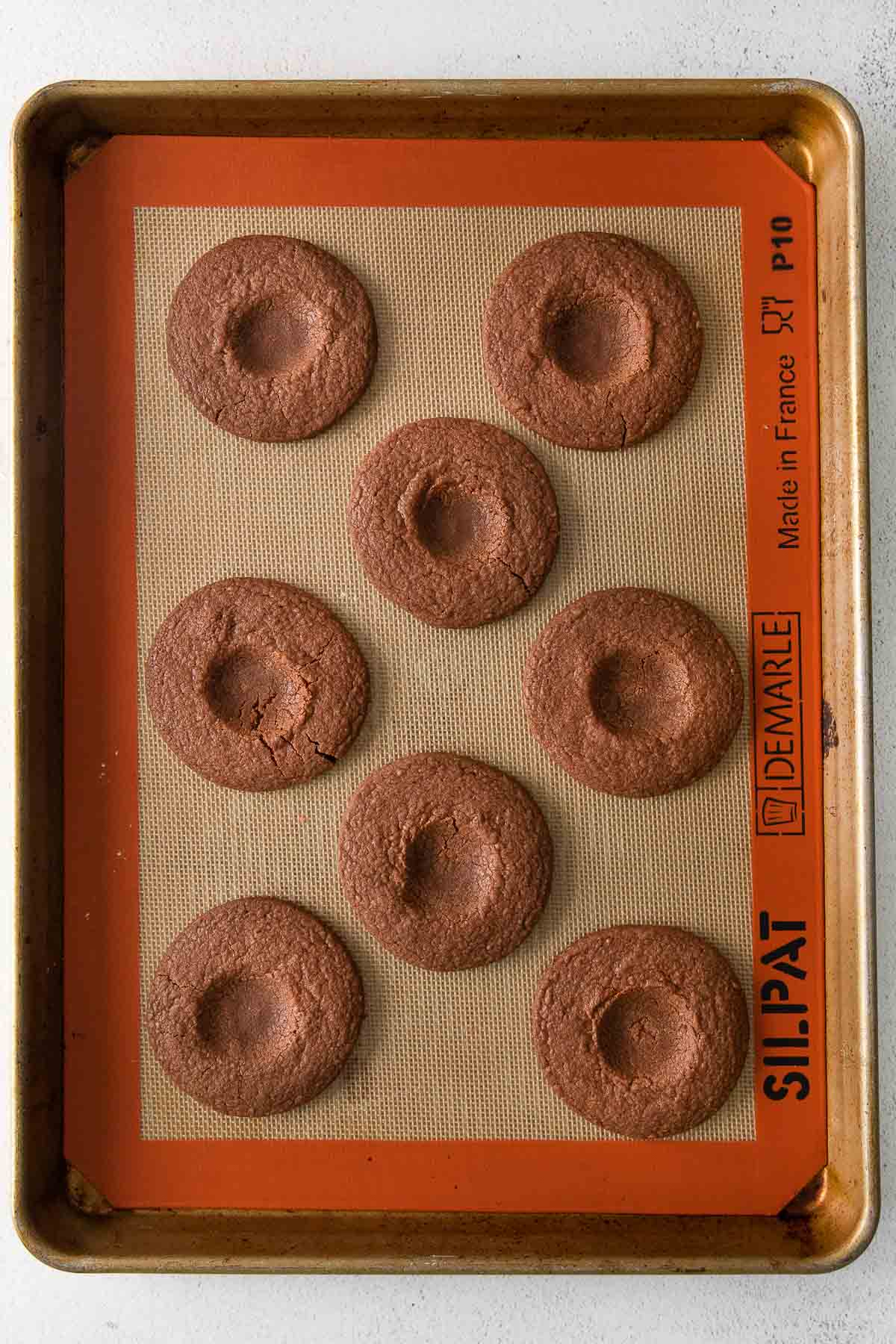 eight chocolate cookies with a pressed thumbprint in the center of each.