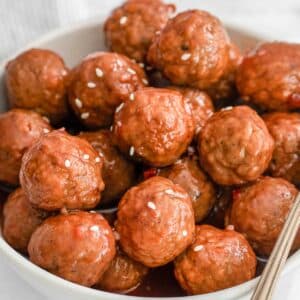 closeup of cranberry meatballs in a white bowl.