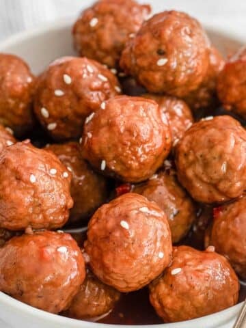 closeup of cranberry meatballs in a white bowl.