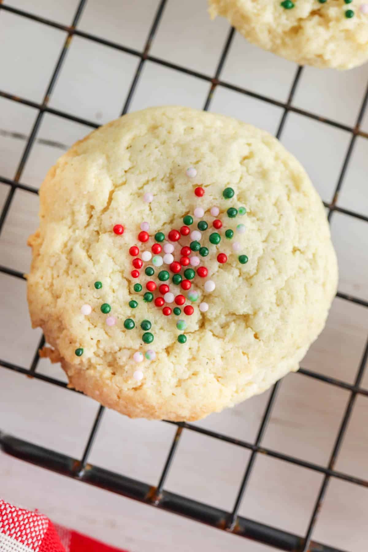 closeup of a sugar cookie with red and green sprinkles on a wire cooling rack.