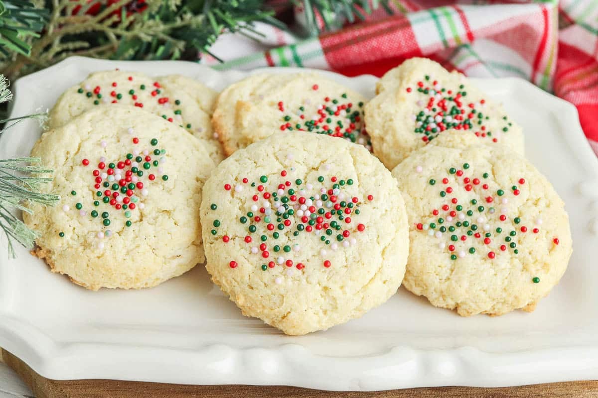 white rectangle serving plate with several cream cheese cookies with green and red sprinkles.