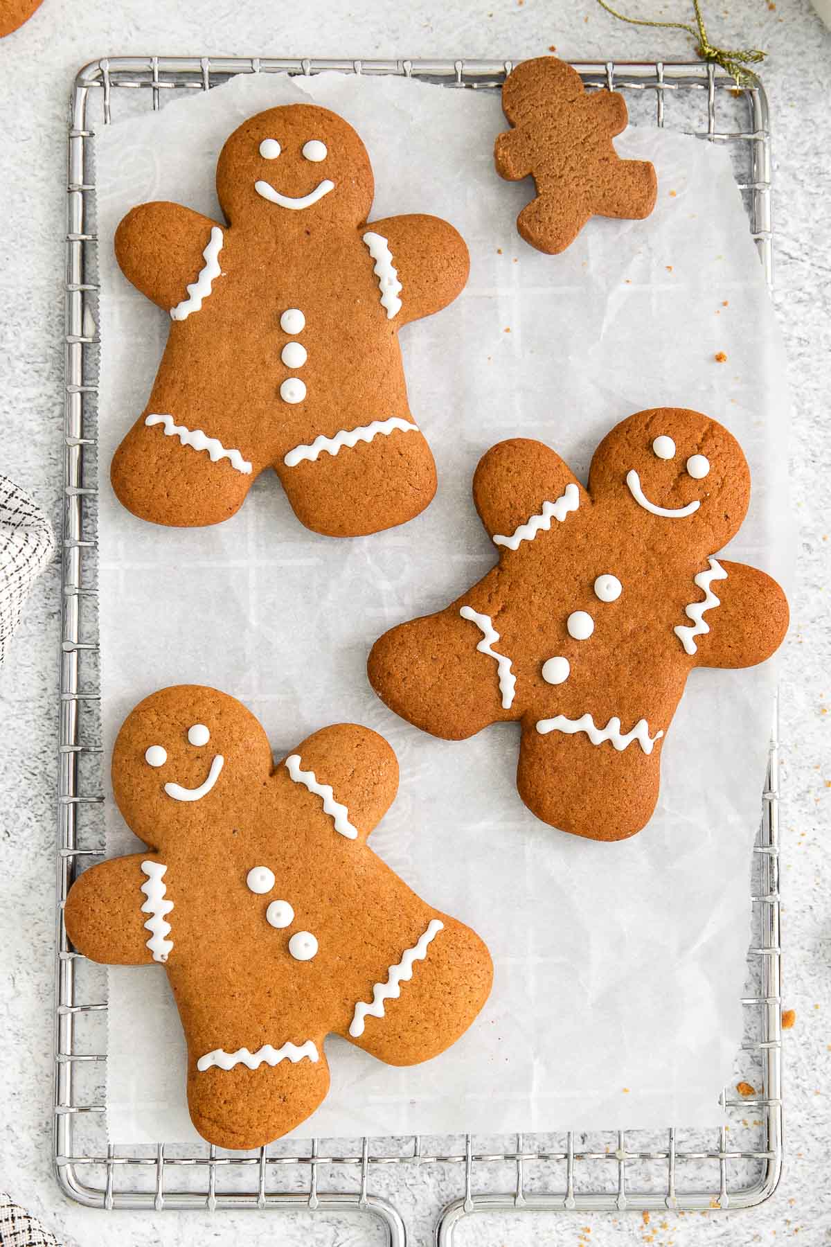 three decorated gingerbread men on a cooling rack with lined with parchment paper.