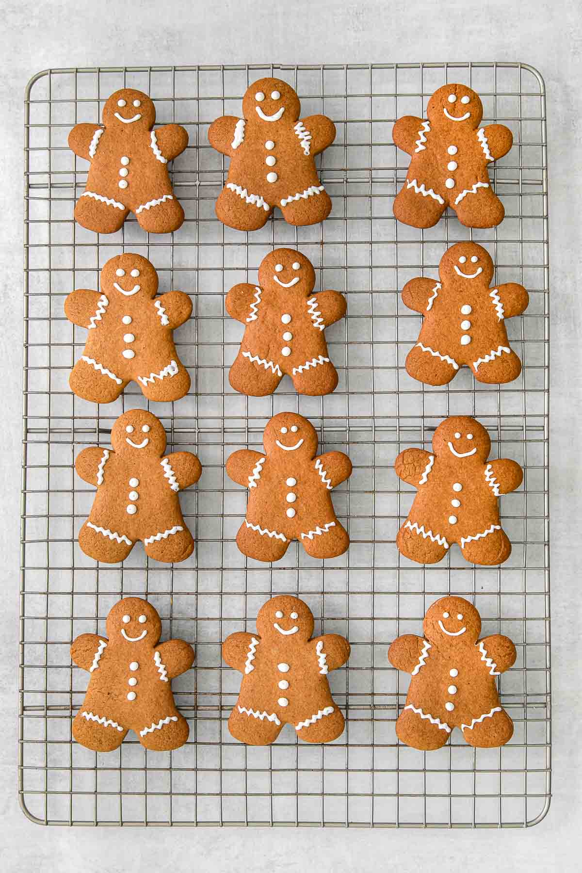 wire cooling rack with twelve gingerbread men decorated with white icing.