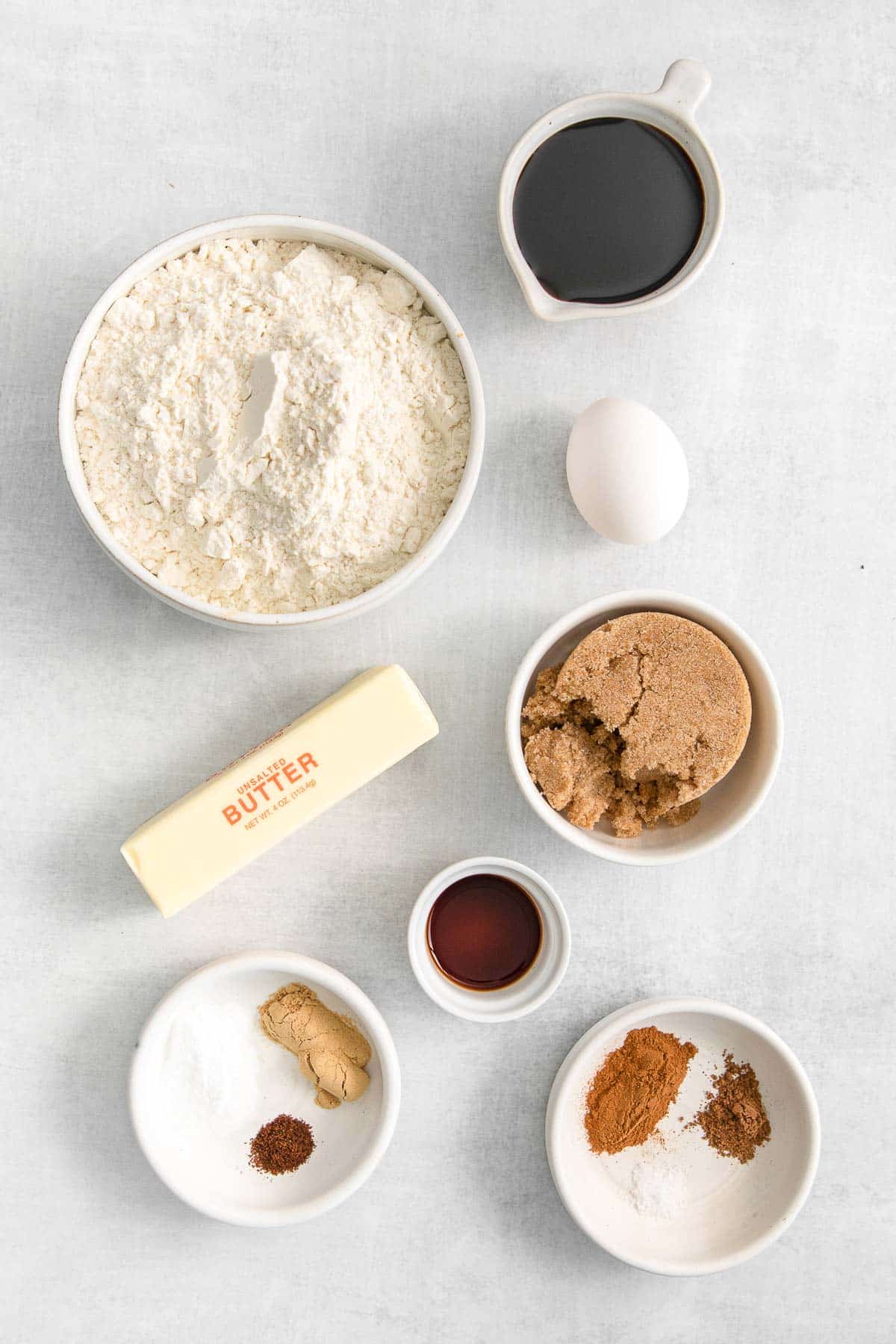 white bowls with flour, brown sugar, butter, molasses, vanilla extract, egg, and fall spices.