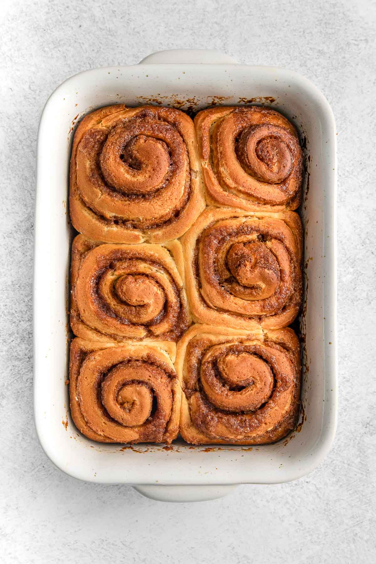 white rectangle baking dish with six cooked cinnamon rolls.