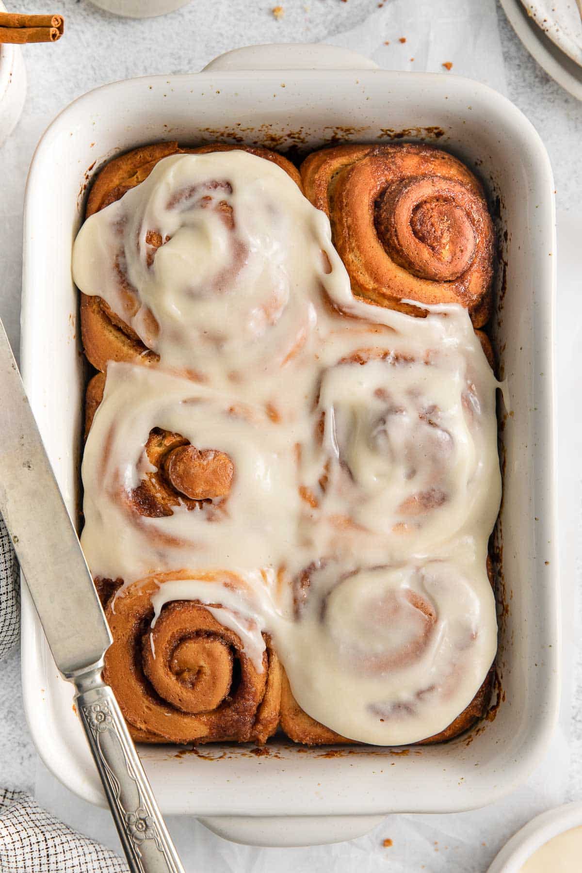 rectangle baking dish with six cinnamon rolls with icing on top.