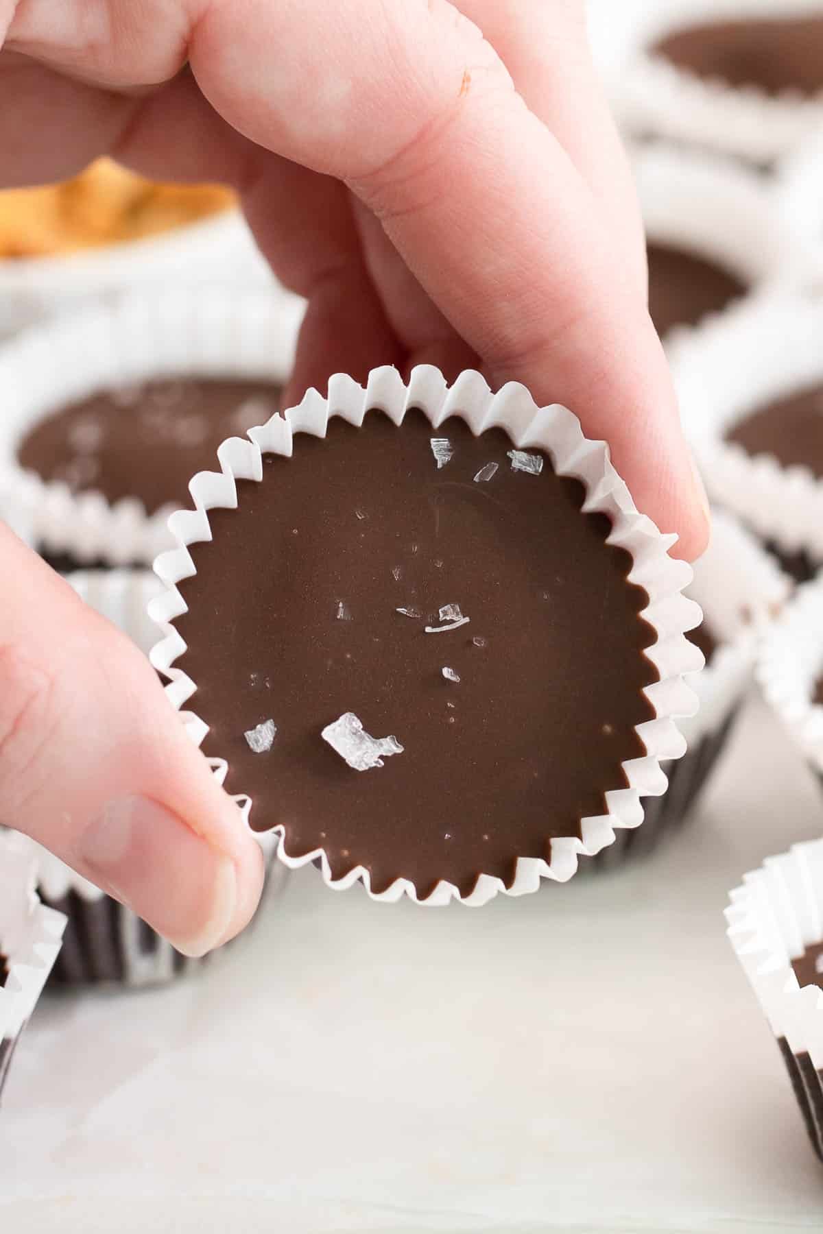 closeup of a homemade peanut butter cup held by a woman's fingers.