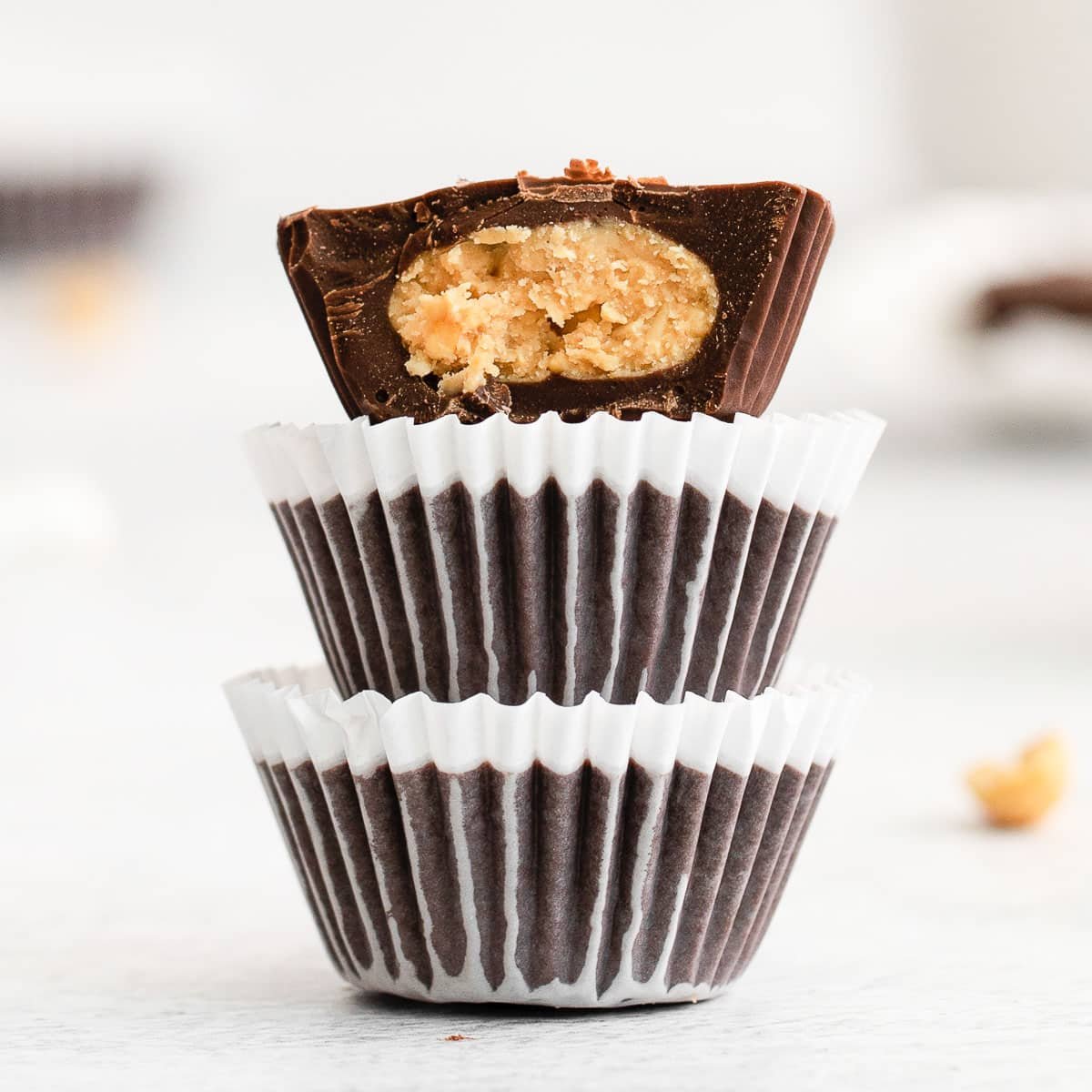 stack of three peanut butter cups with the top one cut in half and peanut butter filling showing.