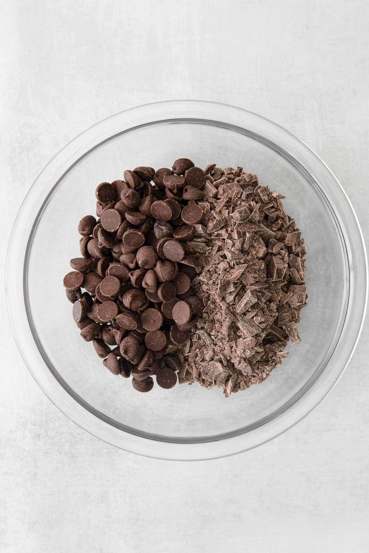 glass mixing bowl with chocolate chips and chocolate bar chunks.