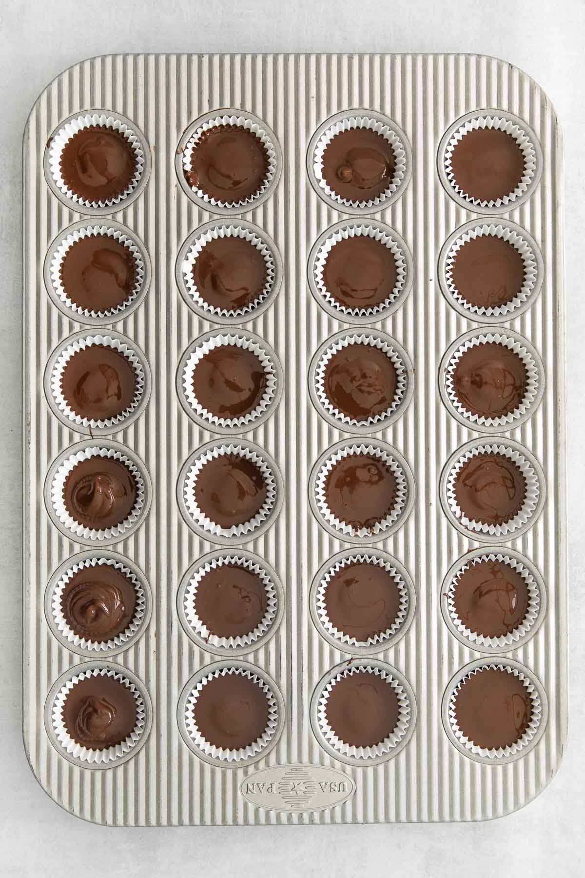 24 chocolate peanut butter cups in a mini muffin tin.