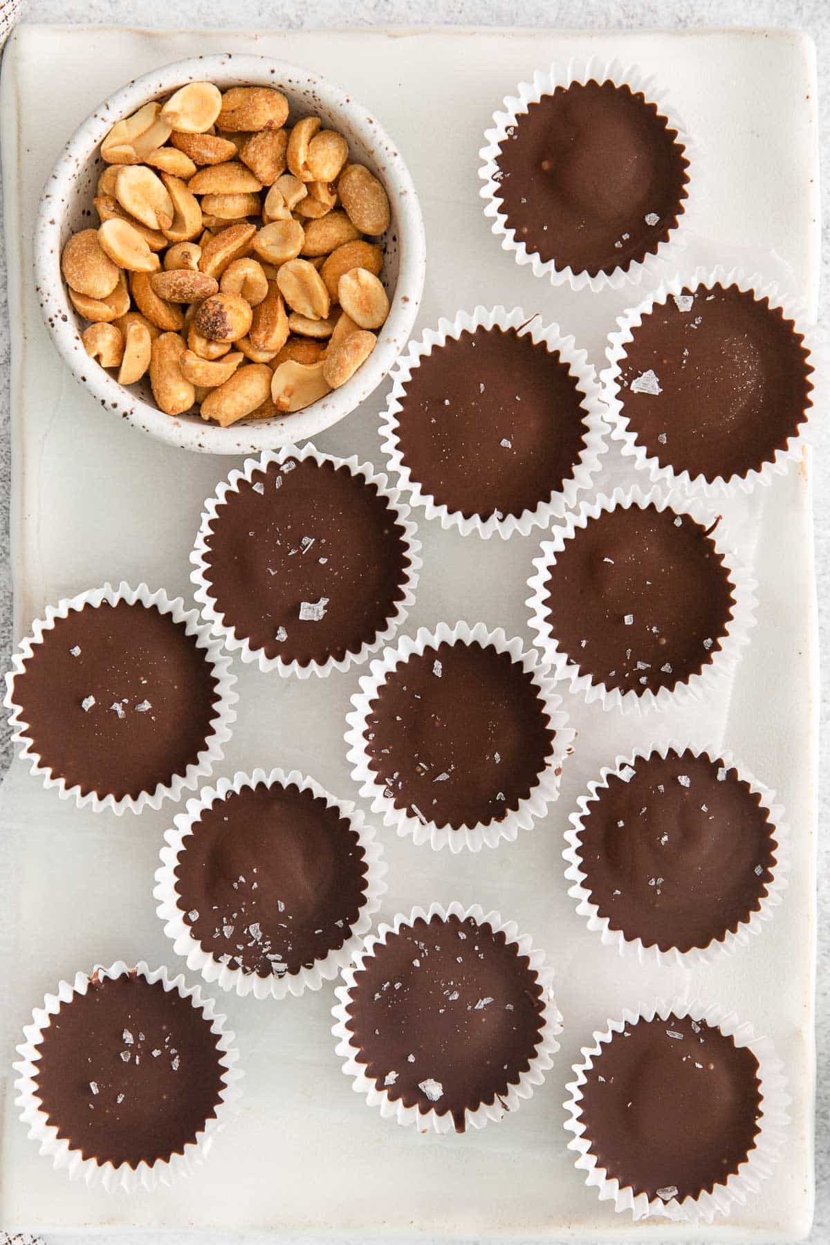 several peanut butter cups in white paper liners on a white countertop.