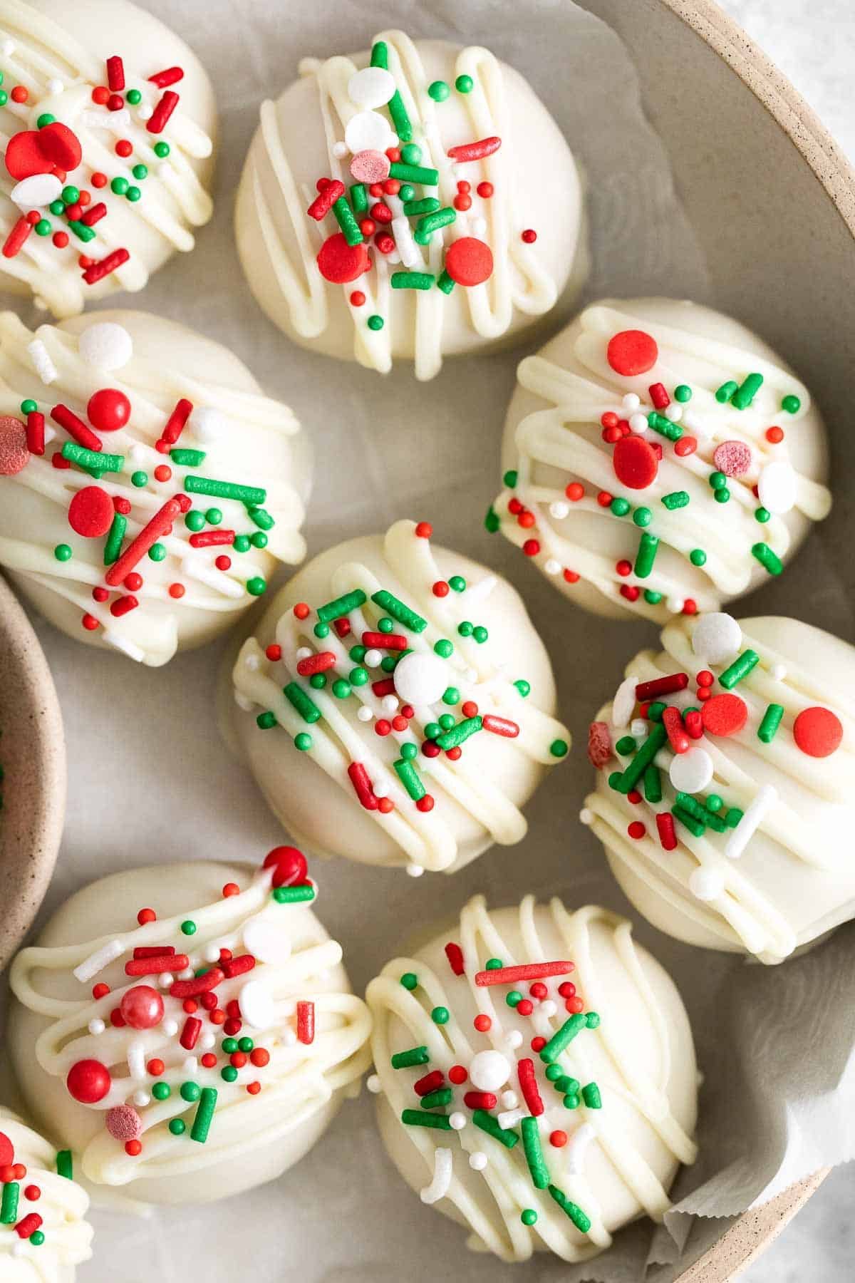 closeup of seven white chocolate covered peanut butter balls with red and green sprinkles.