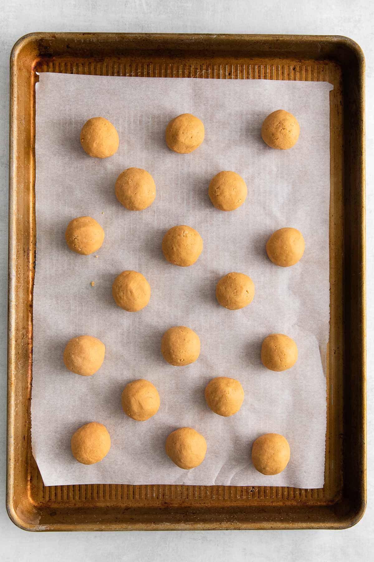 eighteen peanut butter balls on a baking sheet with parchment paper.