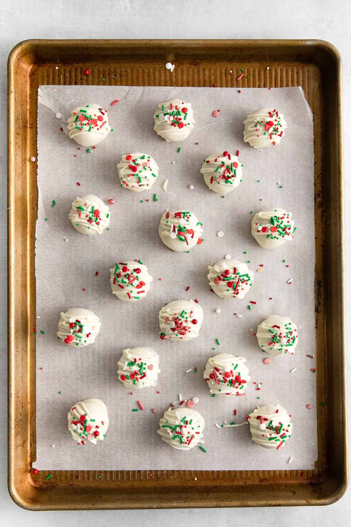 baking sheet with peanut butter snowballs decorated with red, green and white sprinkles.