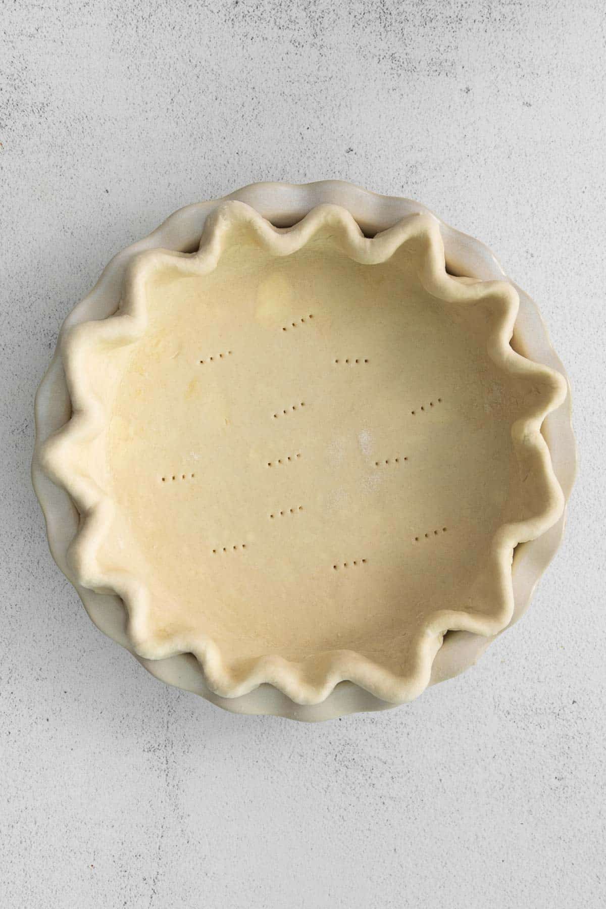 uncooked pie crust with crimped edges in a pie plate.