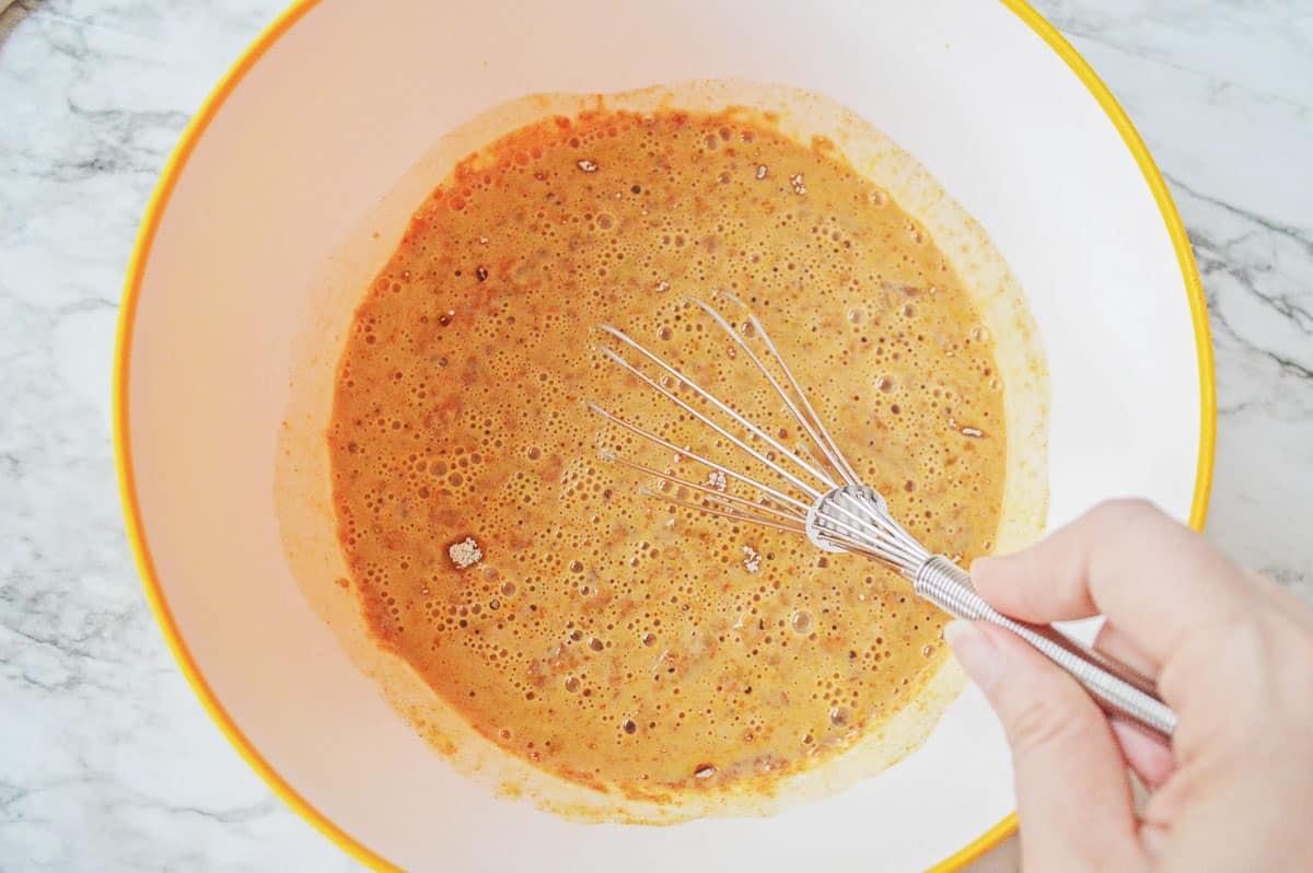 pumpkin pudding mix being whisked in a white bowl.