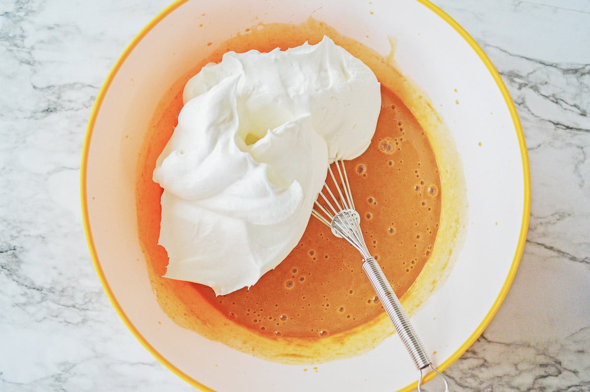 pumpkin pudding mix with whipped topping on top with a whisk.