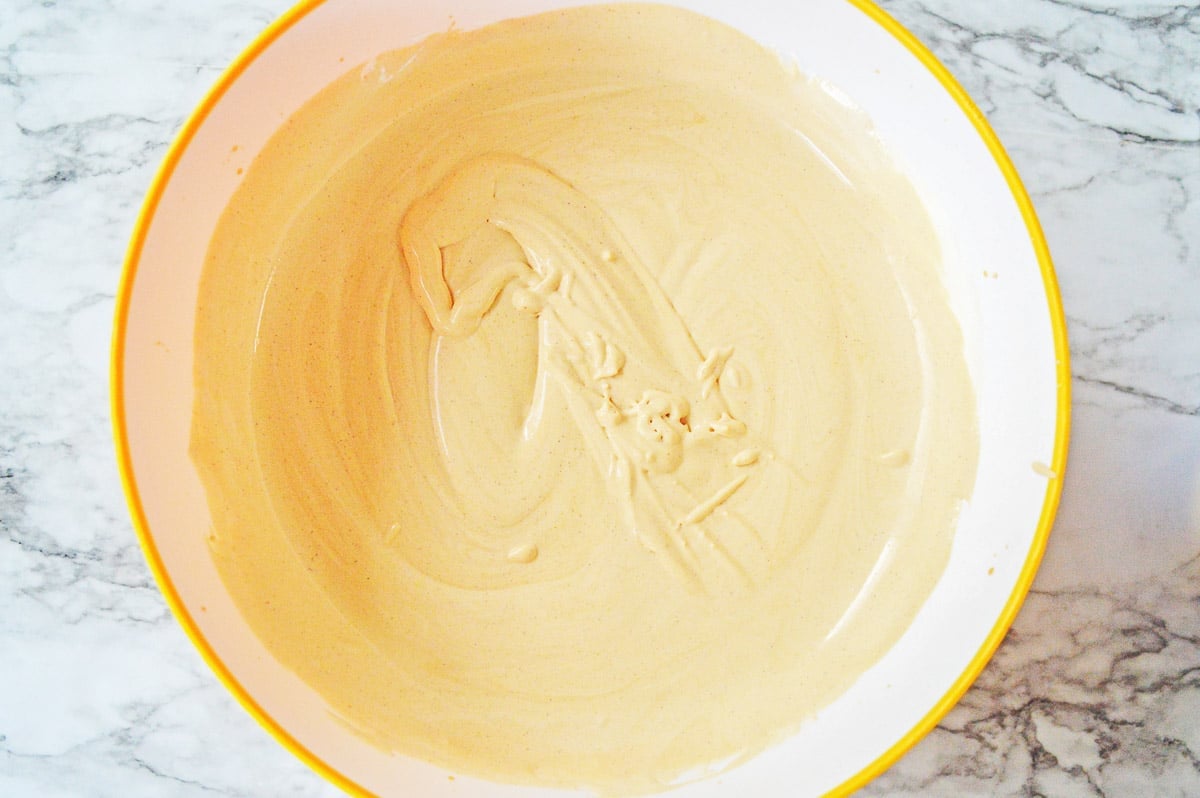 pumpkin pudding mixture in a big white bowl with a yellow rim.
