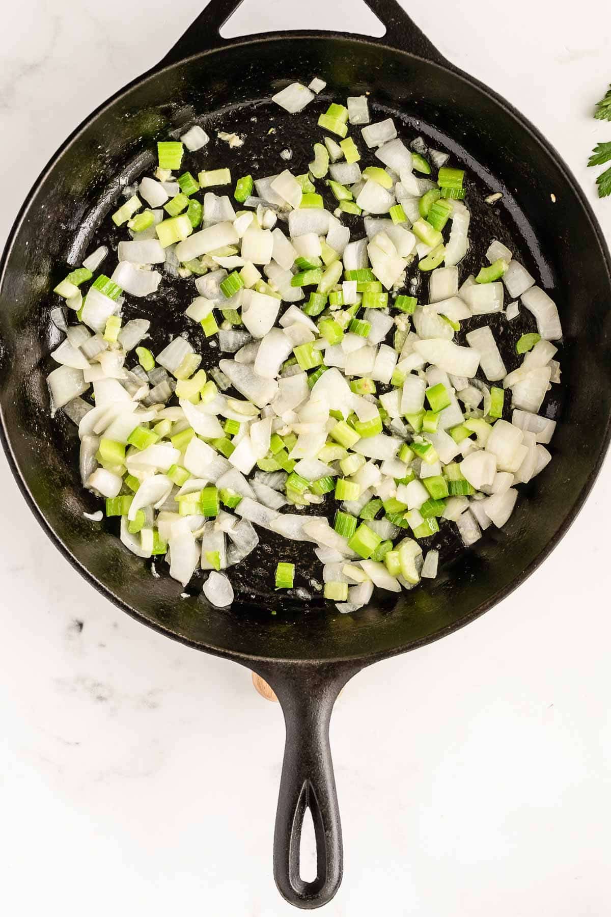cast iron pan with diced onions and celery cooking.