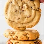 stack of pecan cookies with one being held up over top.