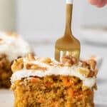 square slice of sheet pan carrot cake with a fork sticking in the top.