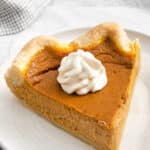 slice of pumpkin pie with whipped cream on top on a white plate with text overlay that reads best easy pumpkin pie.