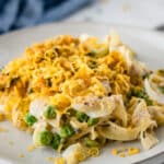 white plate with tuna casserole with eggs noodles, peas and cheesy cornflake topping with text overlay reading easy tuna casserole.