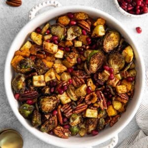 white serving bowl with air fried vegetables - brussel sprouts, butternut squash, parsnips, pecans and pomegranate seeds.