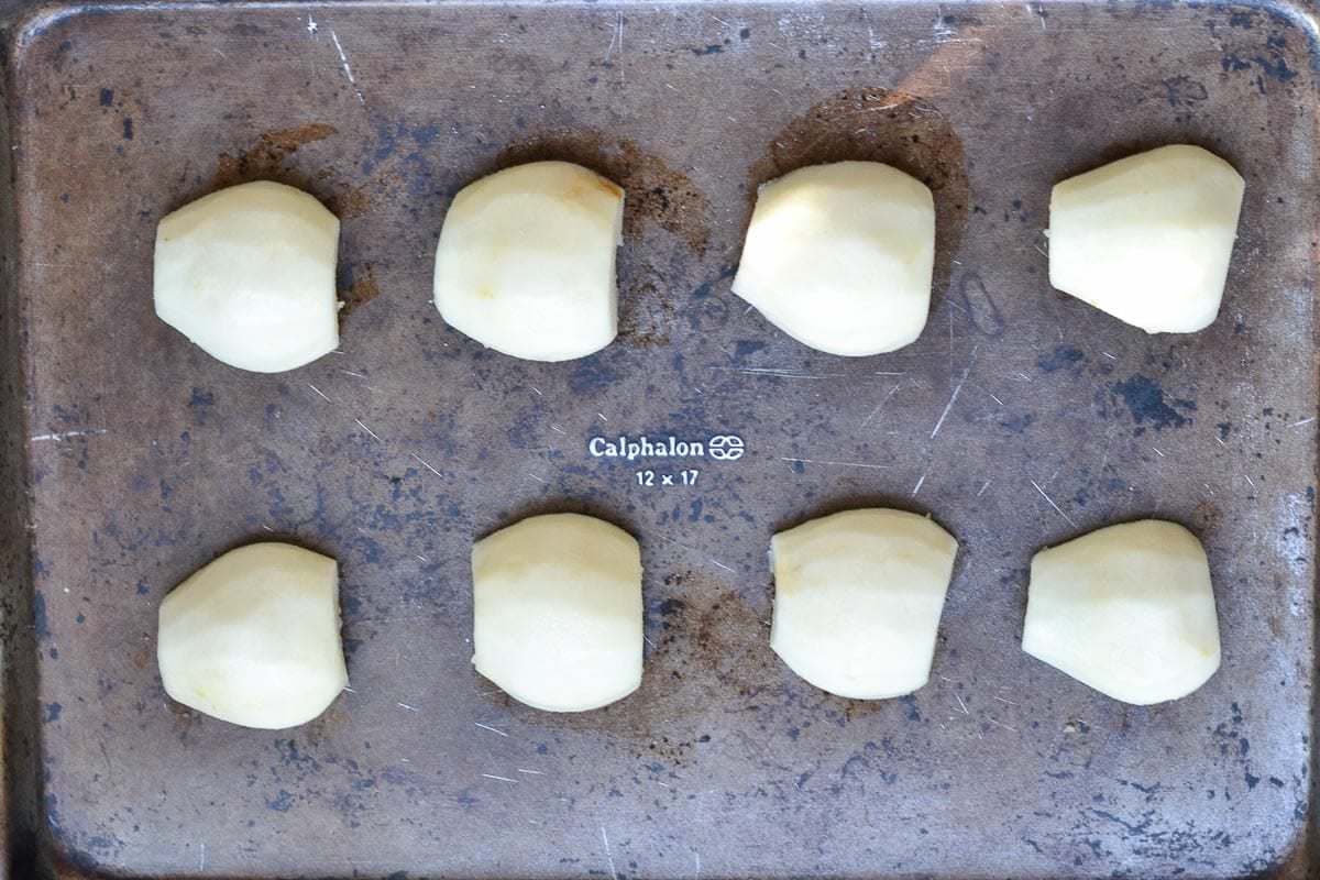 eight peeled pear halves on a baking sheet.