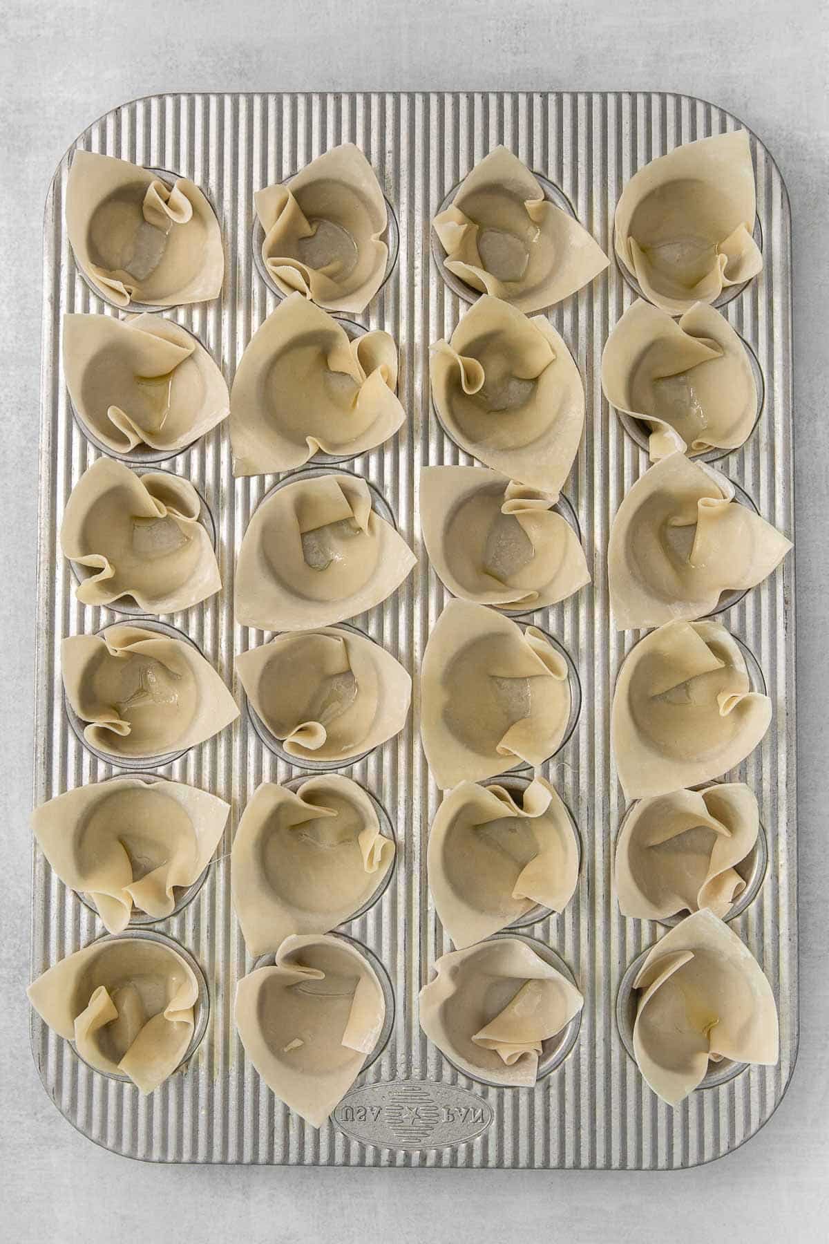 mini muffin tin with wonton wrapper in each hole.