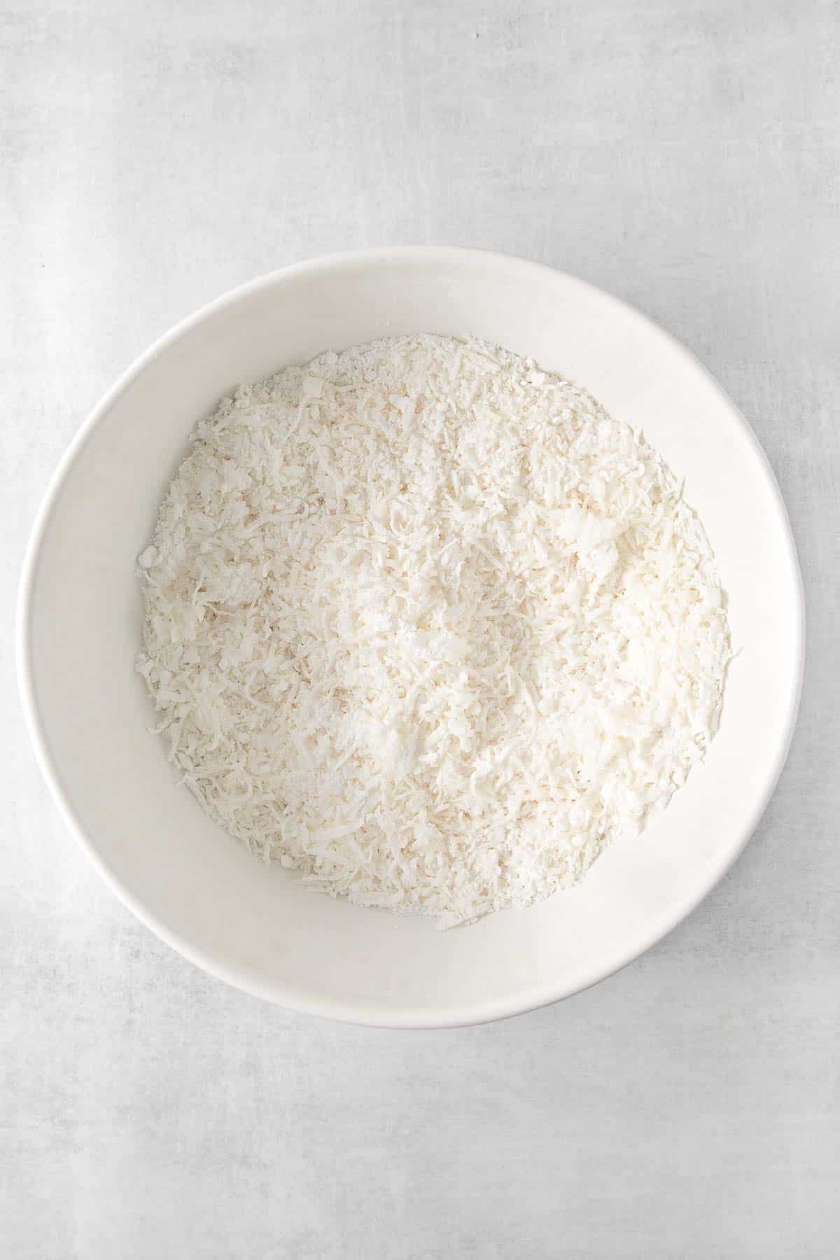 white mixing bowl with shredded coconut.