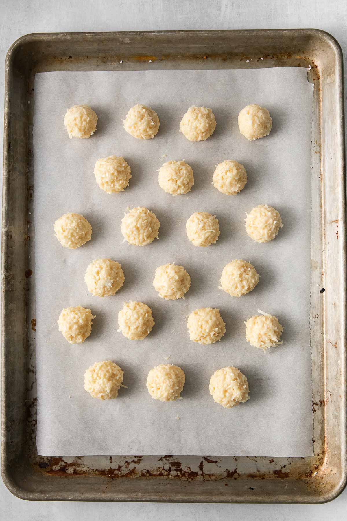 baking sheet with 21 coconut balls lined up.