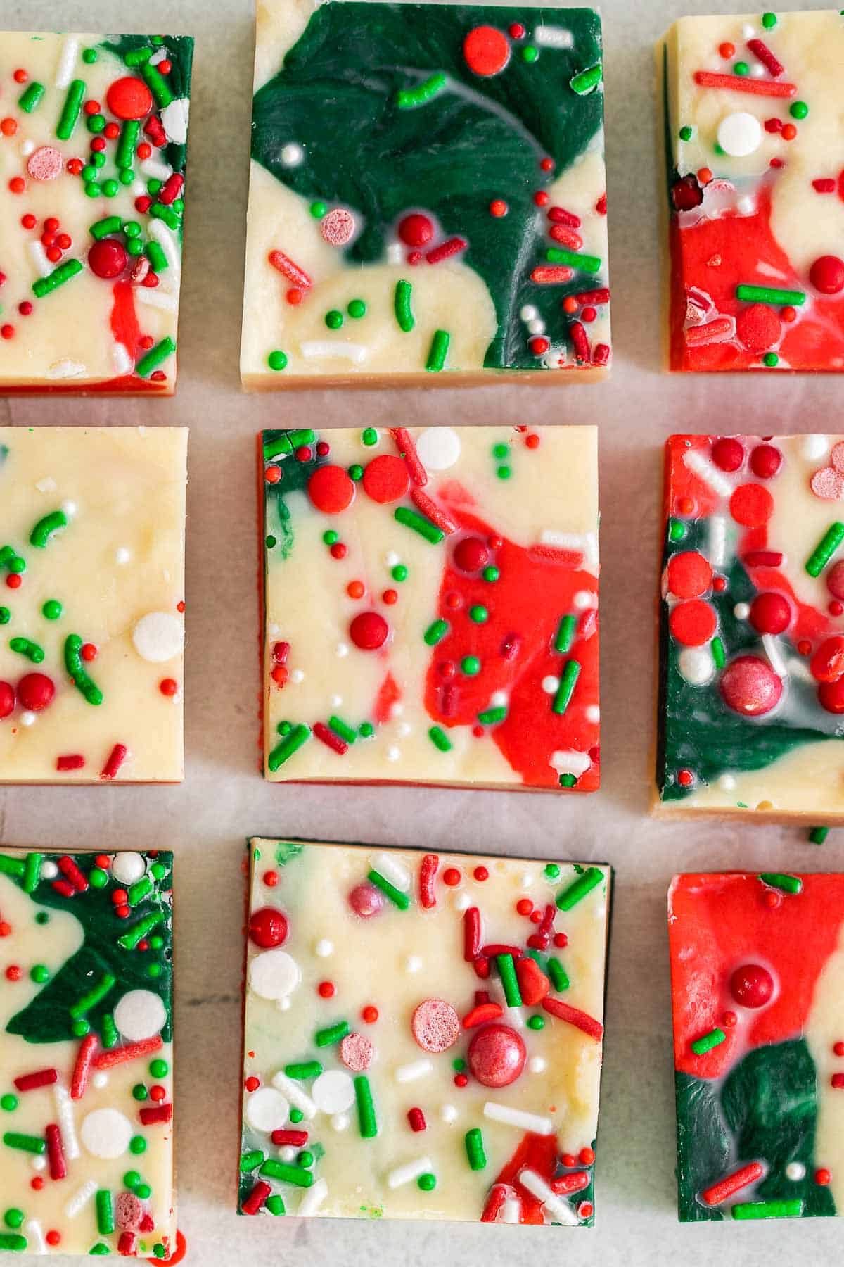 several squares of green red and white Christmas fudge with holiday colored sprinkles.