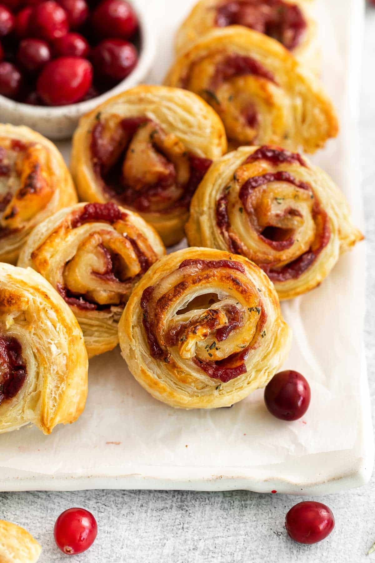 several puff pastry cranberry brie bites on a plate.
