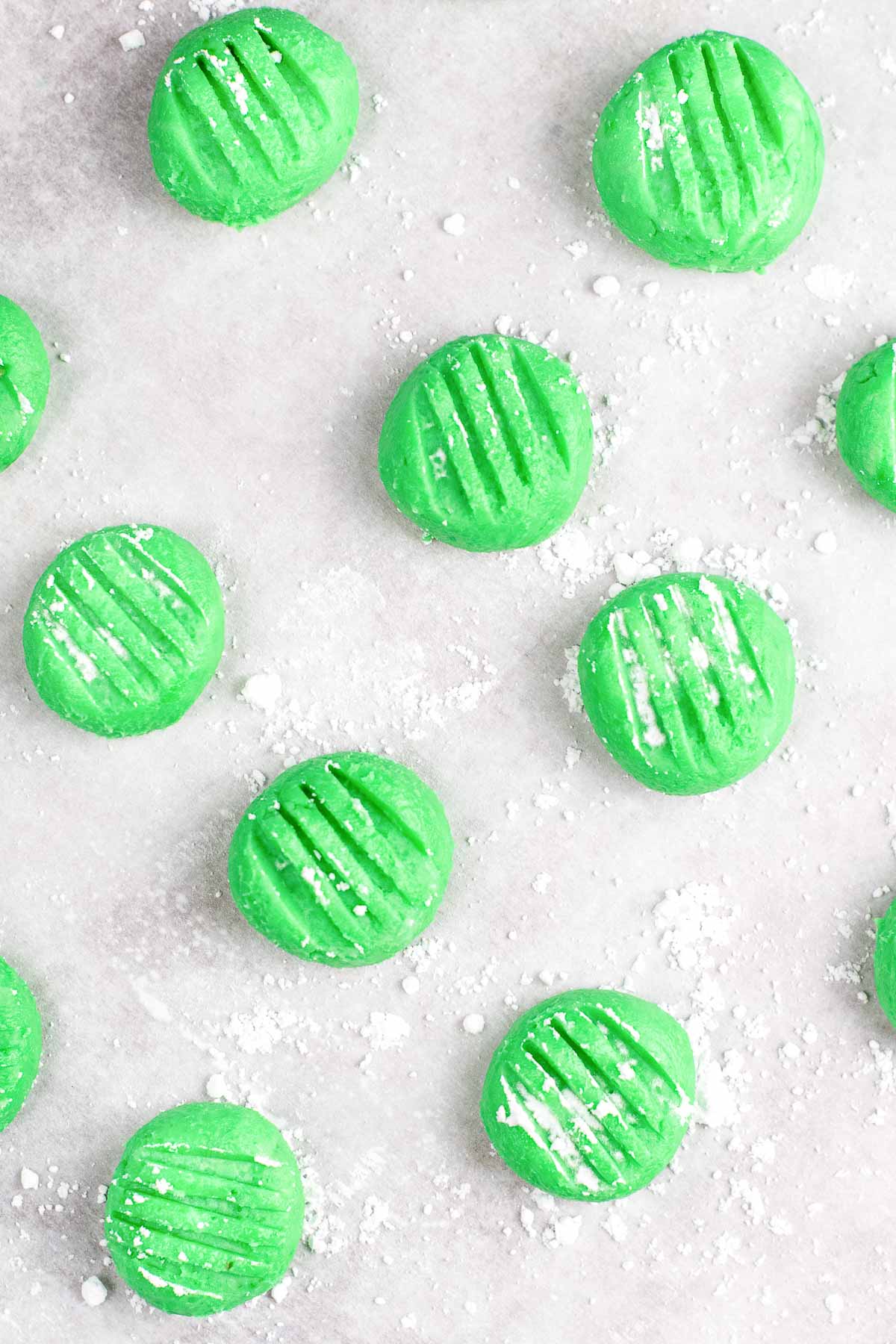 several green cream cheese mints on white parchment paper.