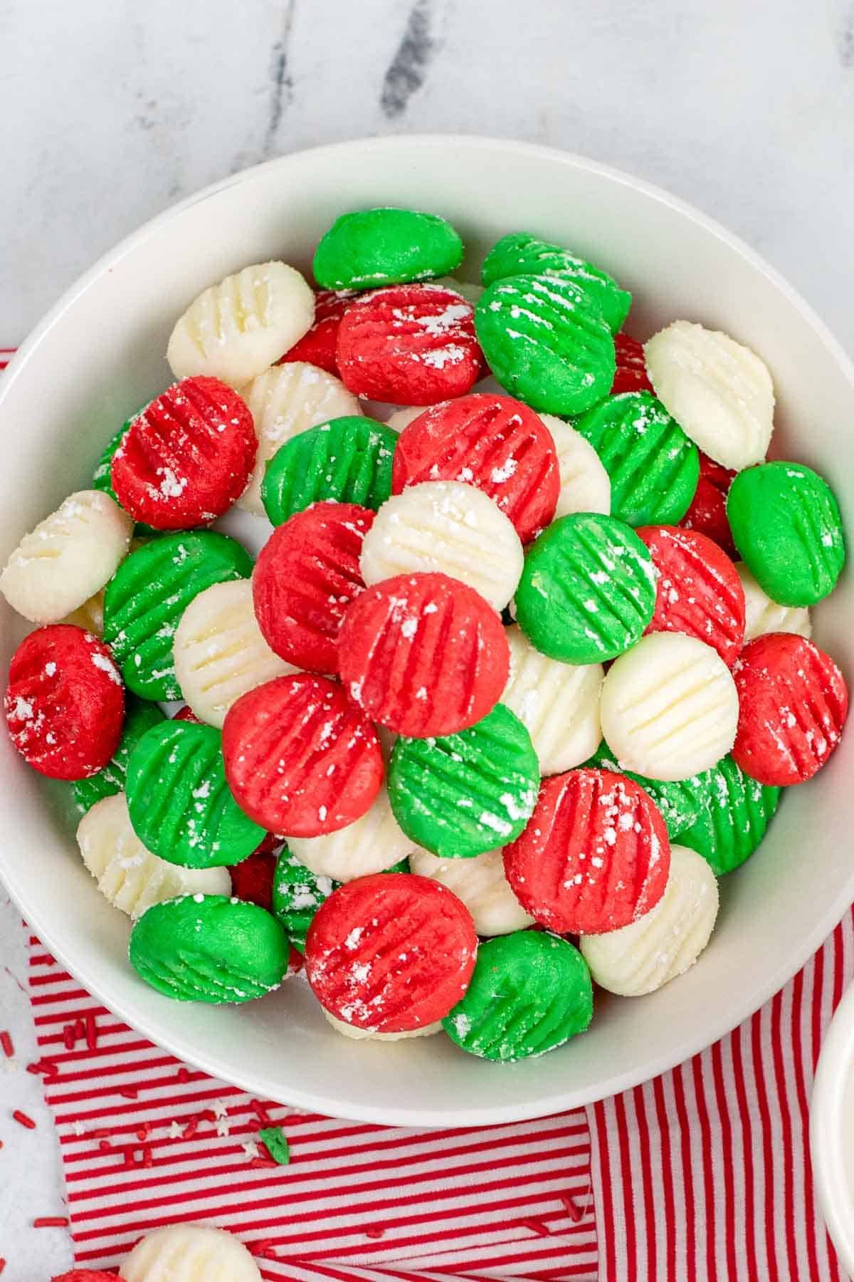 white bowl full of red, green and white cream cheese mints.
