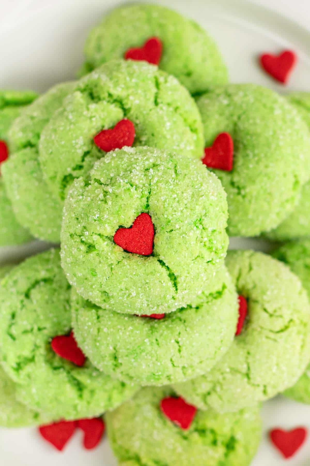 closeup of several green grinch crinkle cookies with red hearts in the center.
