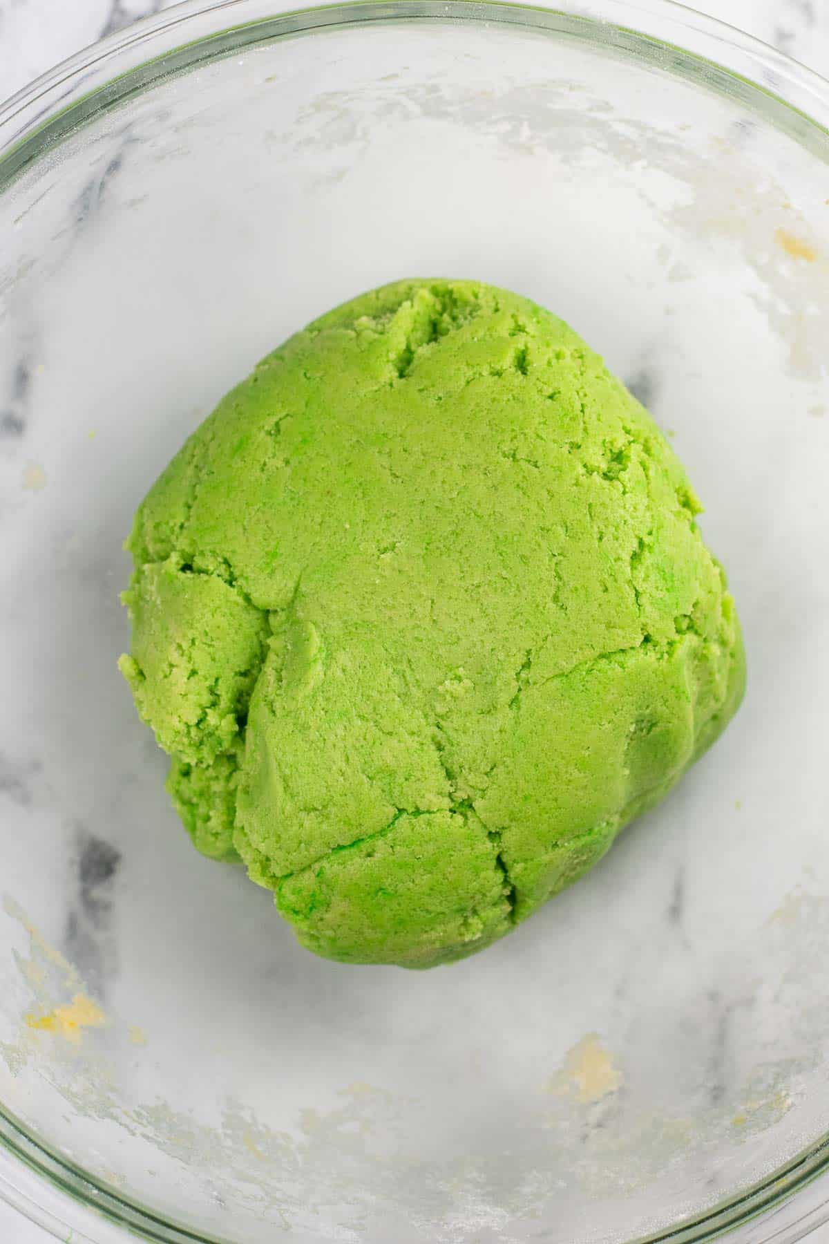 green cookie dough in a glass mixing bowl.