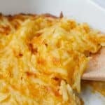 closeup of a scoop of hashbrown casserole on a wooden spoon.