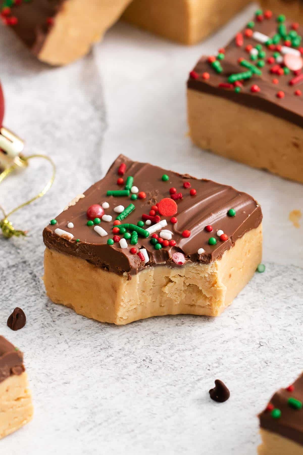 closeup of a peanut butter bar topped with chocolate and holiday colored sprinkles.