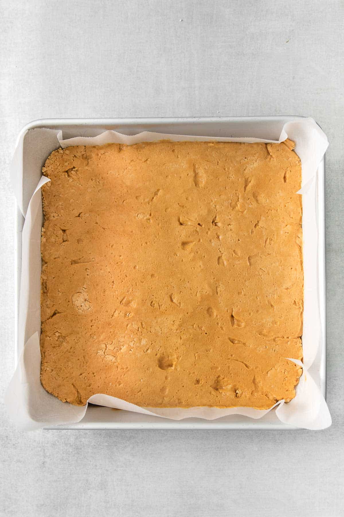 peanut butter and powdered sugar mixture pressed into a square metal baking dish.
