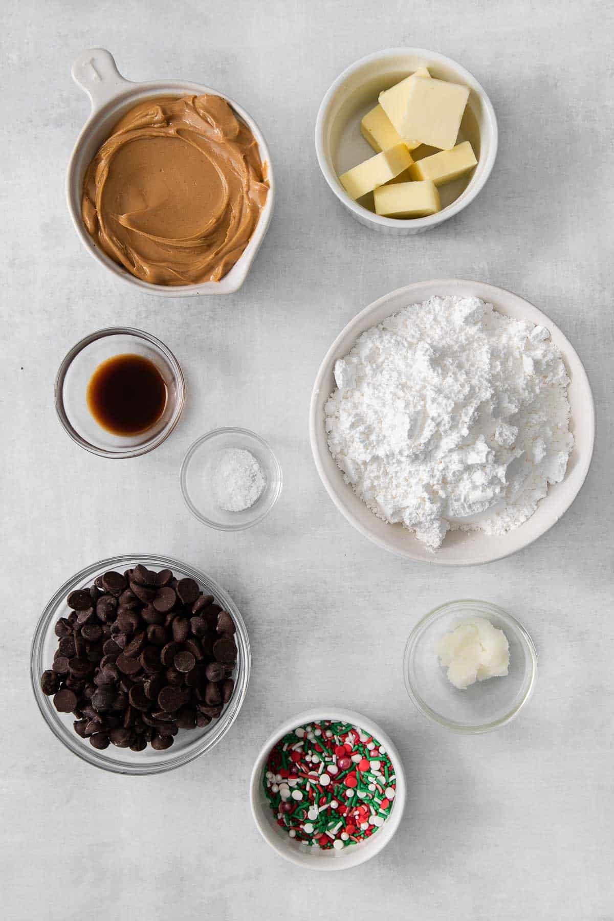 several bowls with ingredients for peanut butter bars - cream peanut butter, powdered sugar, chocolate chips, vanilla extract, salt.